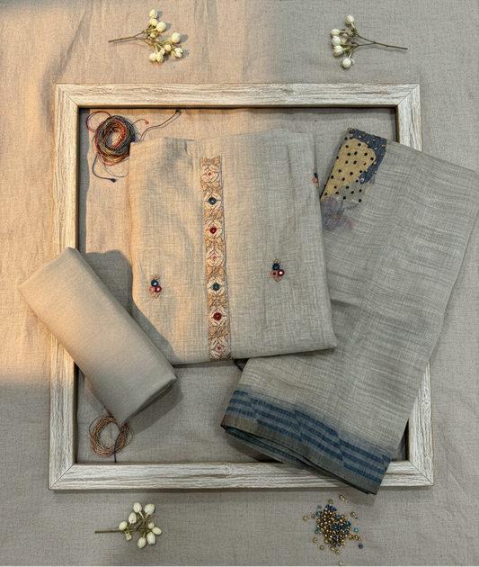 Gray traditional outfit with embroidered details on a wooden tray against a gray background